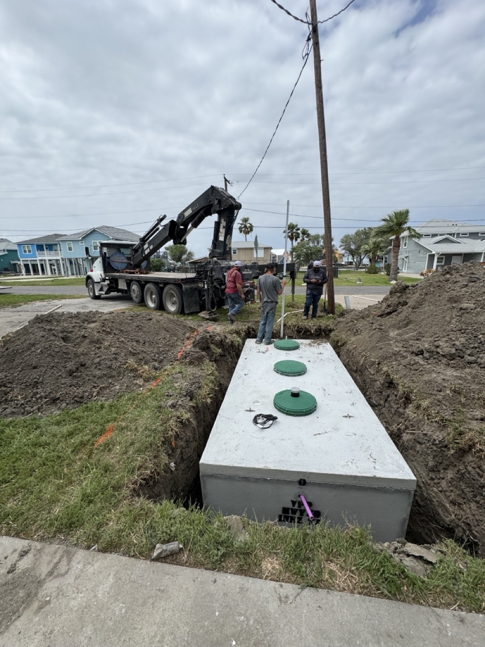 Crane truck setting a septic tank on a residential street